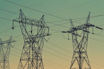 Electricity transmission towers against a sunset sky.