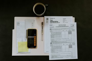 A dark wooden table with tax documents, a phone, and a coffee cup.