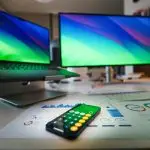 A modern desk setup with dual monitors, financial charts, and a calculator.
