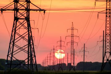 High-voltage power lines against a sunset sky.