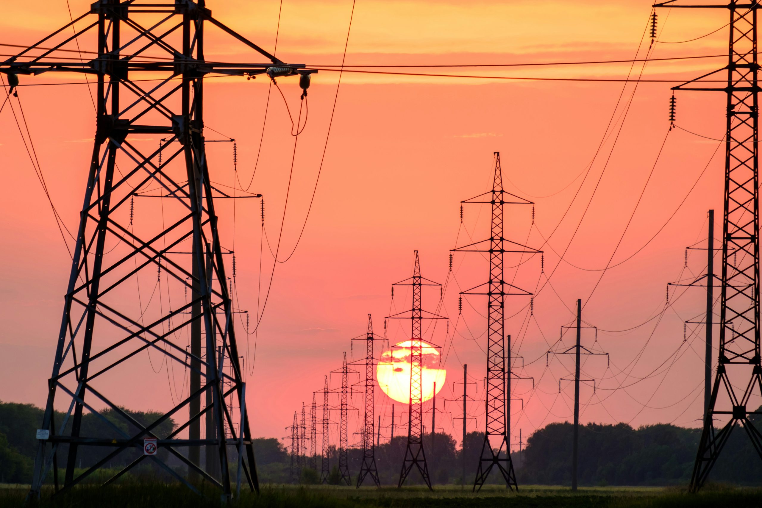High-voltage power lines against a sunset sky.