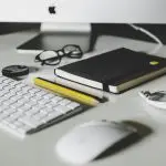 A workstation with a keyboard, notebook, and accessories.