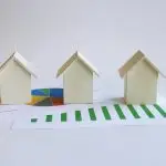 Paper models of houses with financial charts.