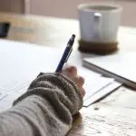 A person using a calculator while taking notes.