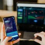 A person using a mobile phone with a financial dashboard.
