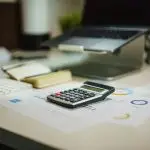 A financial desk setup with a calculator, documents, and digital elements.