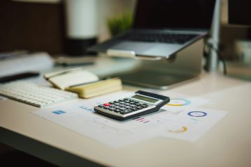 A financial desk setup with a calculator, documents, and digital elements.
