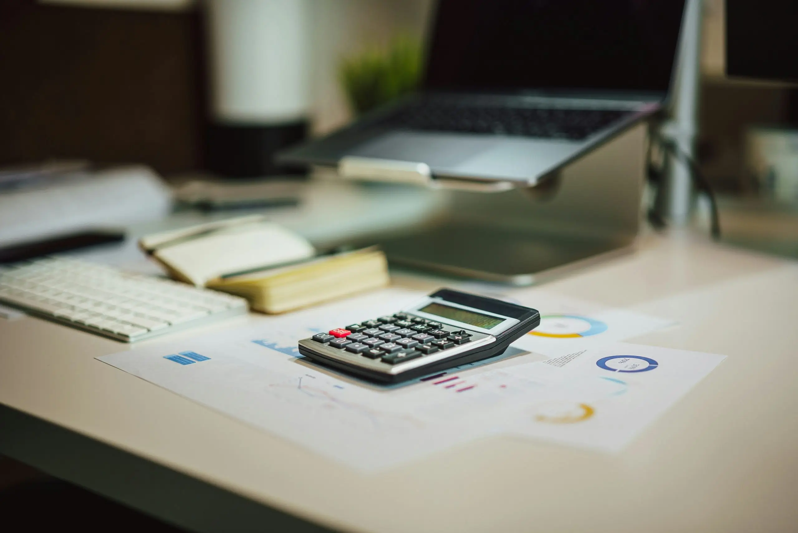 A financial desk setup with a calculator, documents, and digital elements.