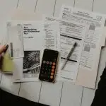 A person calculating withholding tax with a pen and calculator.
